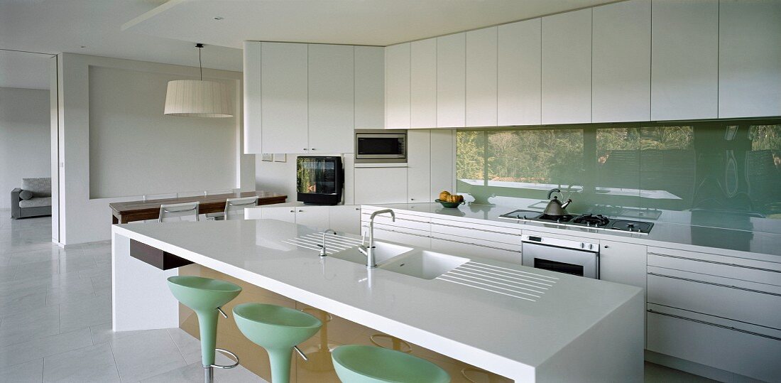 weiße Designerküche mit Küchenblock im offenen Wohnraum