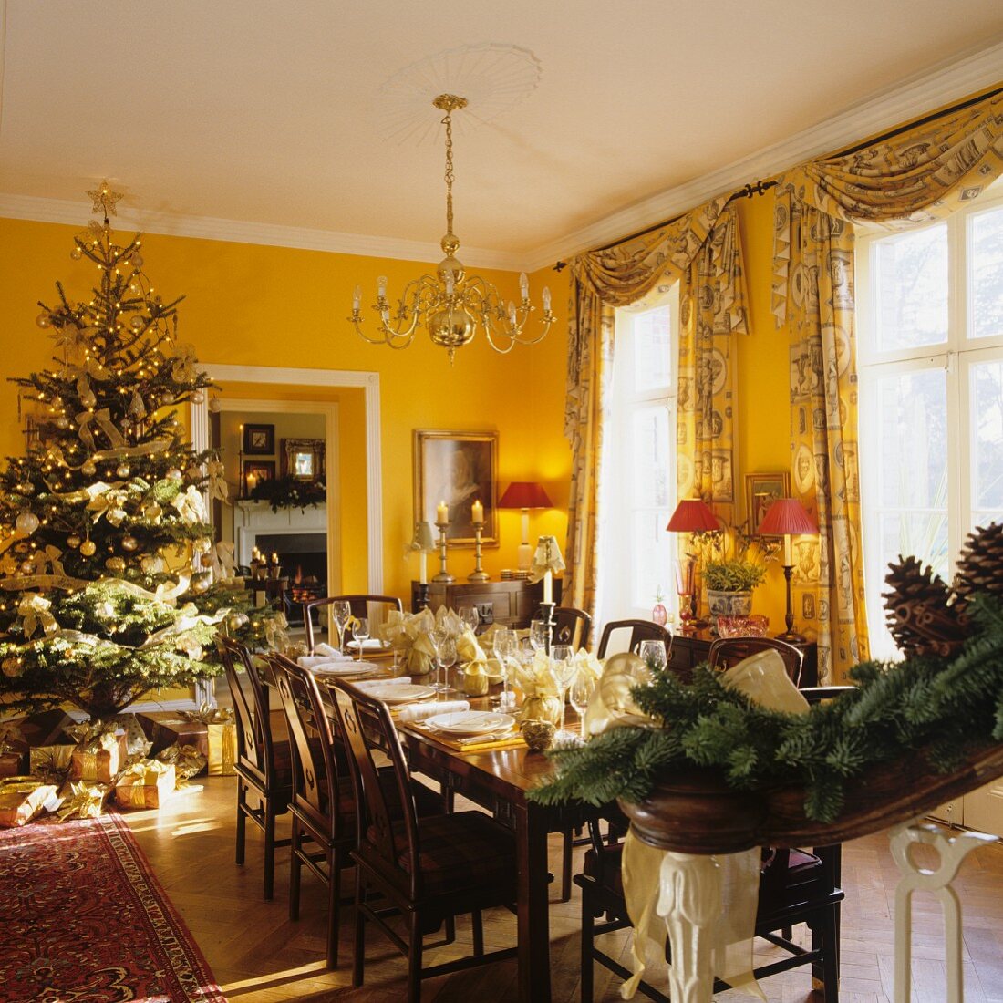 Festive, set dining table and Christmas tree in yellow-painted dining room