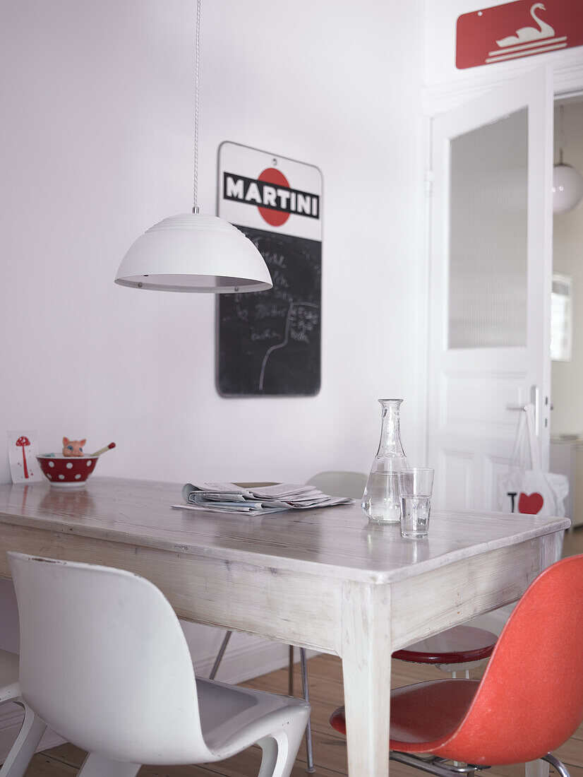 White dining table, red chair and pendant light in kitchen