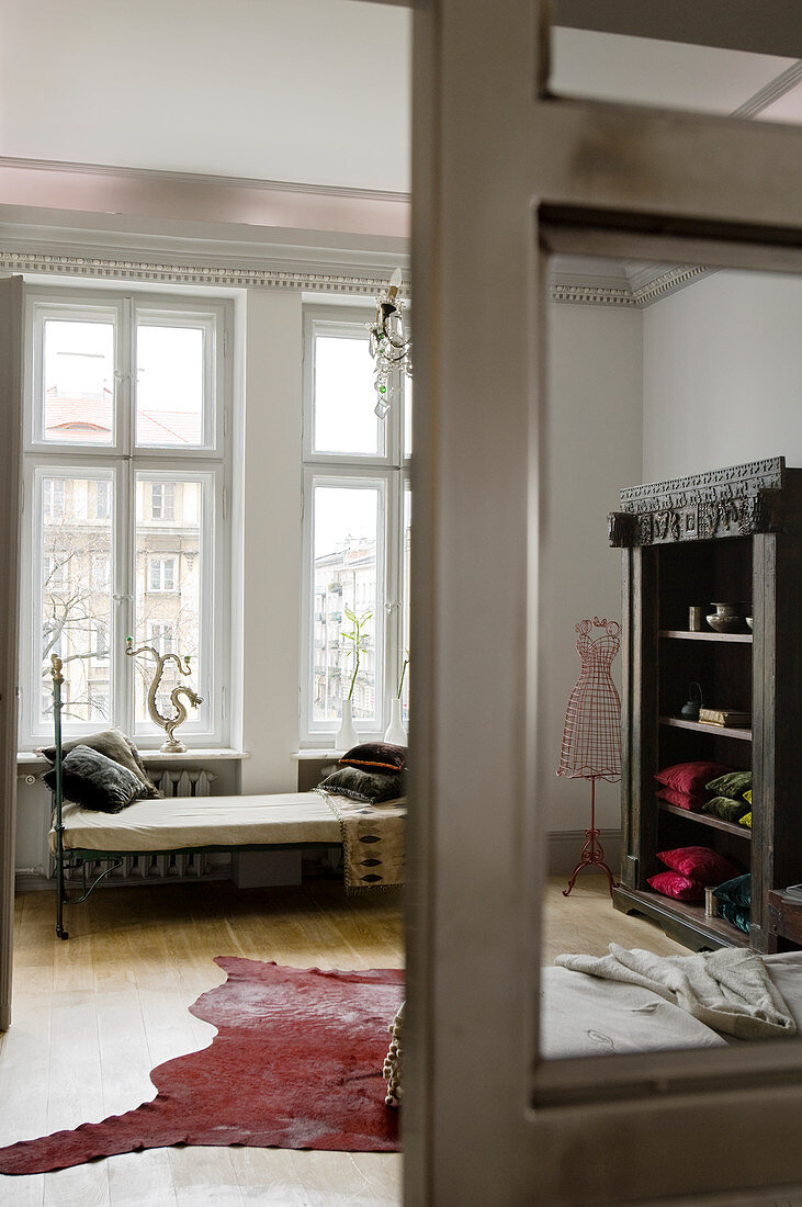 Blick durch offene Glastür in hohes Altbauzimmer mit Sammlerstücken im traditionellem Flair