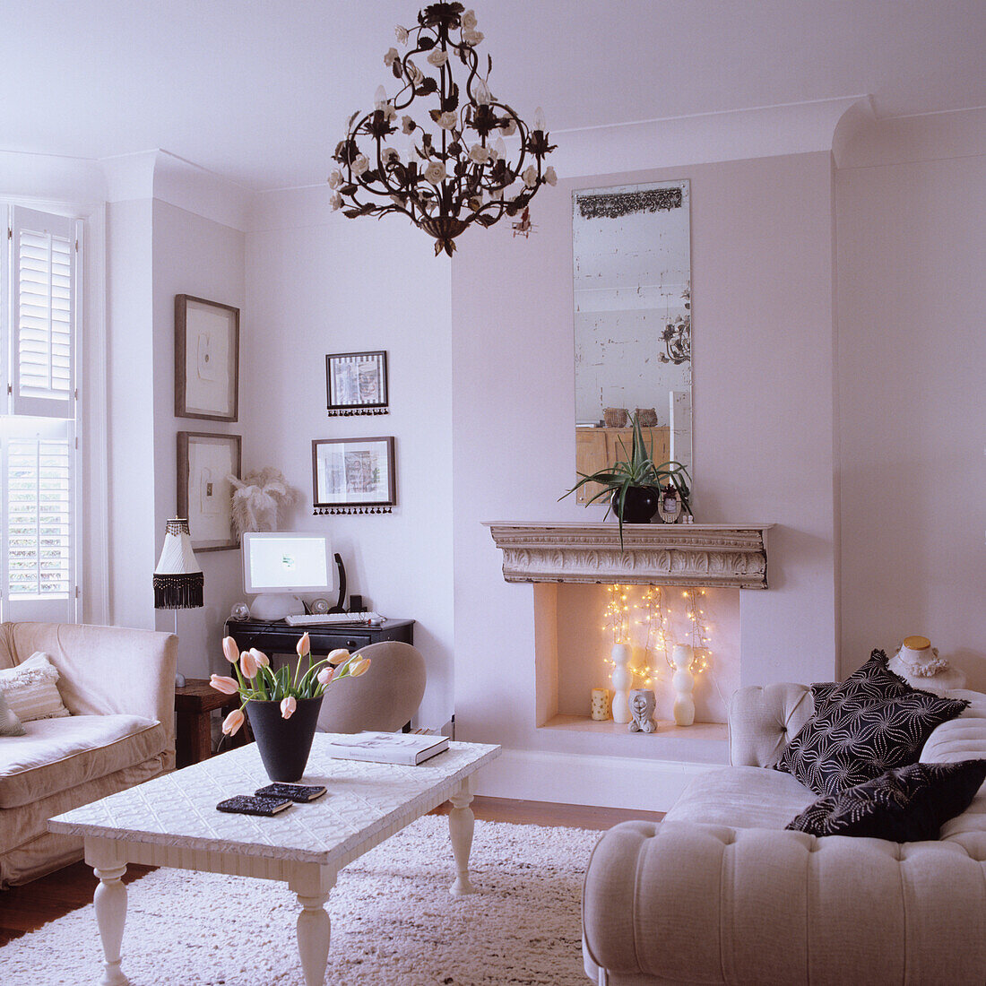 Living room in cream-coloured decor with fireplace and tulips on the coffee table