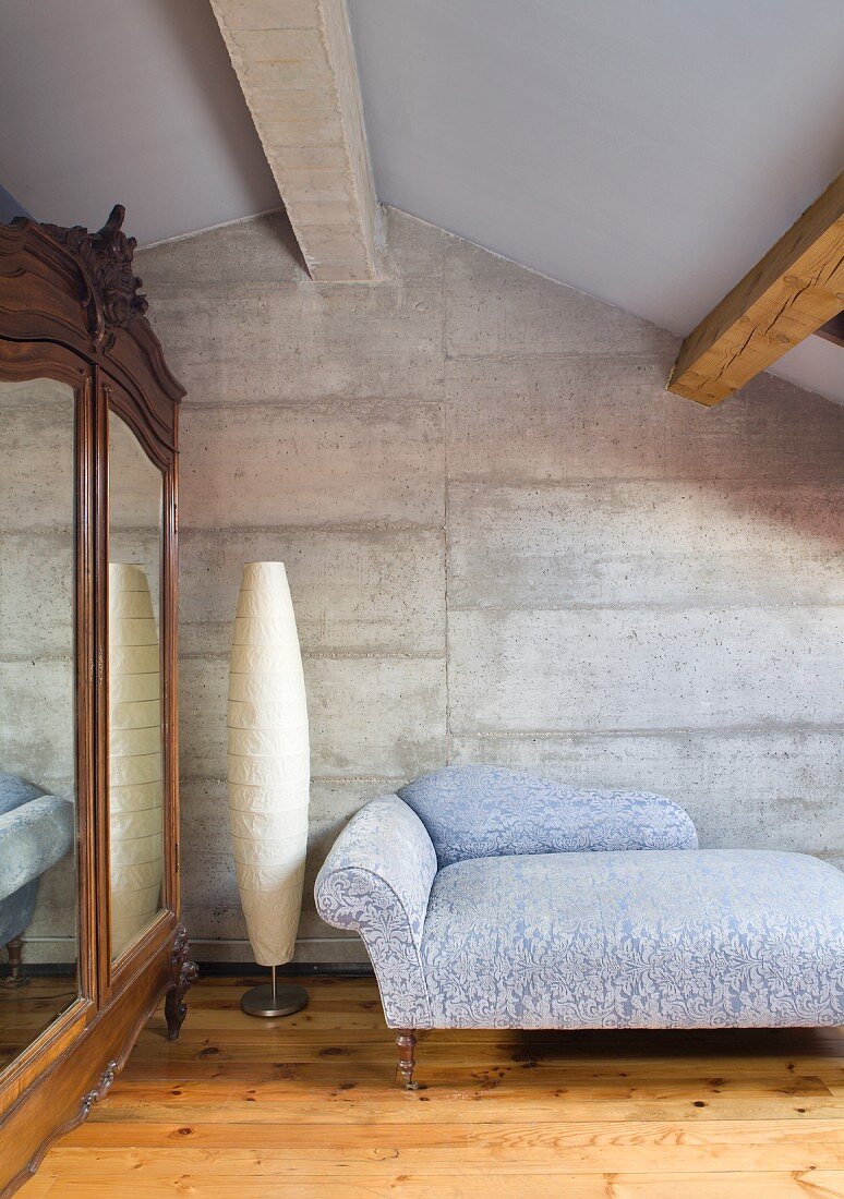 Grosser Kleiderschrank mit Spiegeltür und ein Tagesbett in einem Gästezimmer mit Betonwand