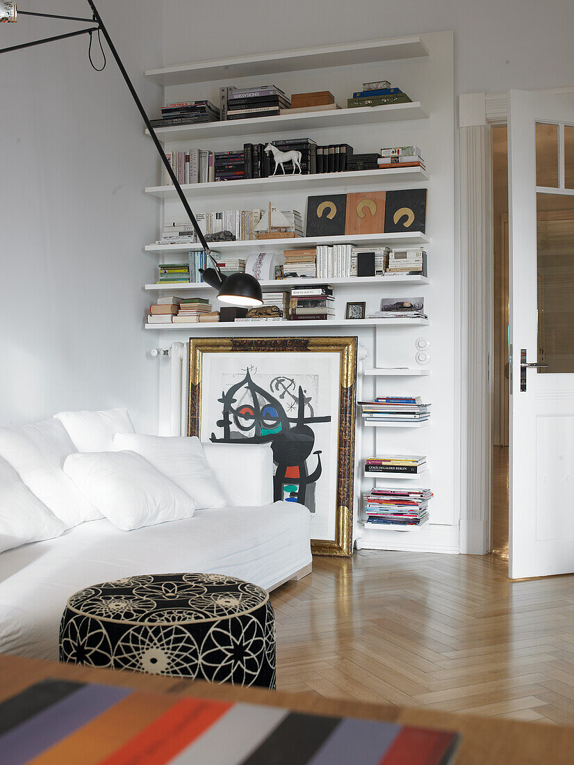 Living room with wall shelves, artwork and white sofa