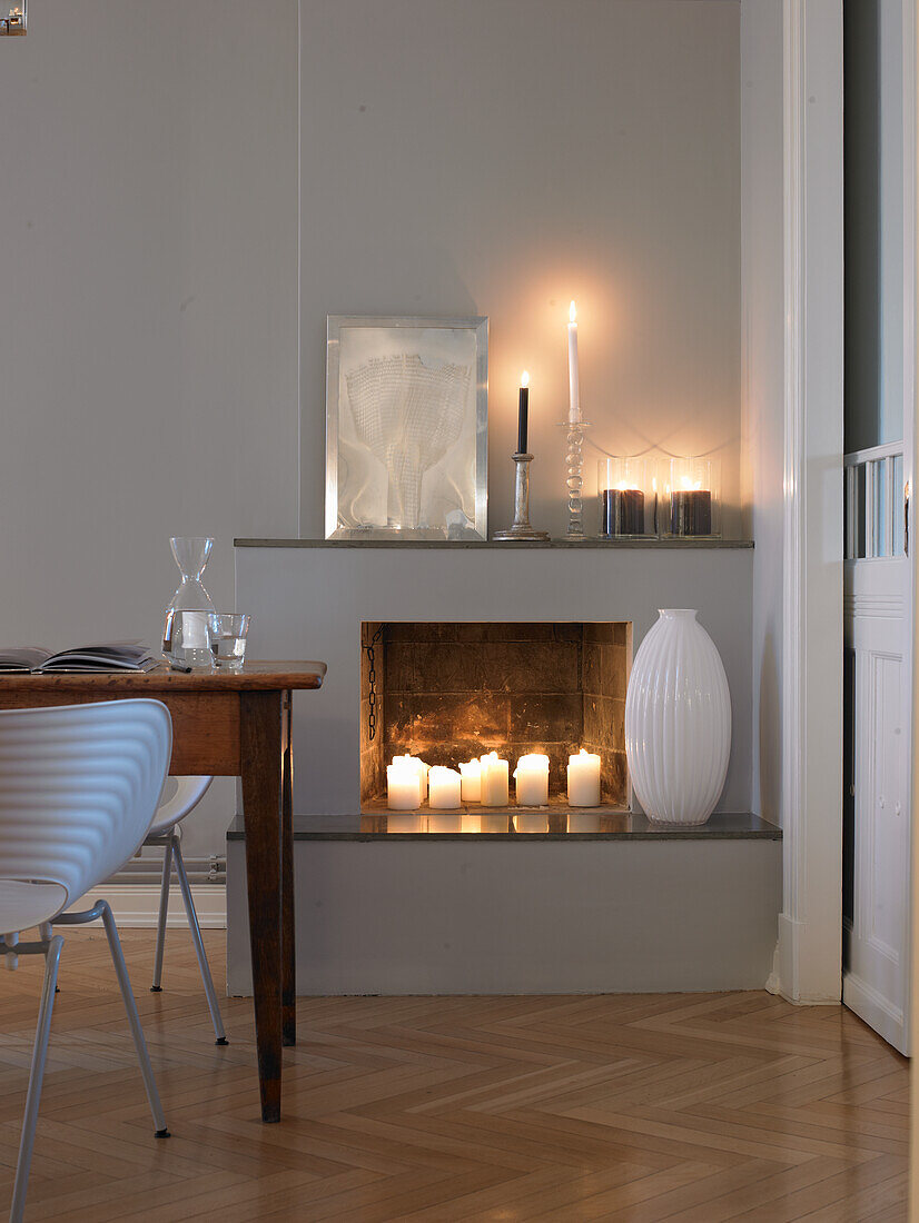 Kamin mit Kerzen, weißem Dekor und Holztisch im Wohnzimmer