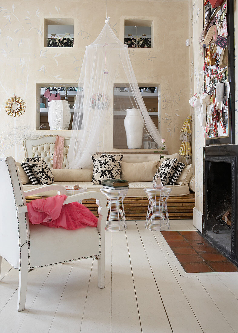 Sessel mit weißem Lederbezug und Sofa aus Bambusstangen vor Kamin in modernem Landhaus