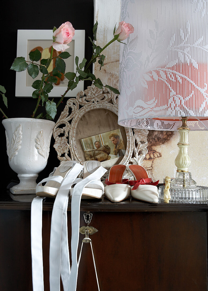 Damenschuhe neben Blumenvase und Tischlampe mit Stoffschirm