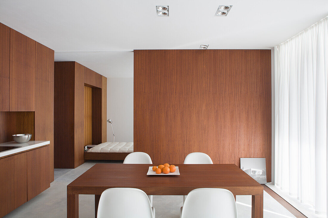 Dining table with white chairs in modern room with wooden furniture and wooden partition wall