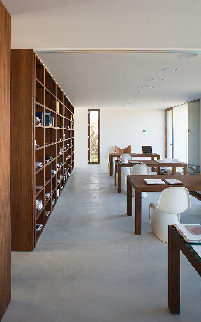 Bücherregal aus Holz in Arbeitszimmer mit Betonboden