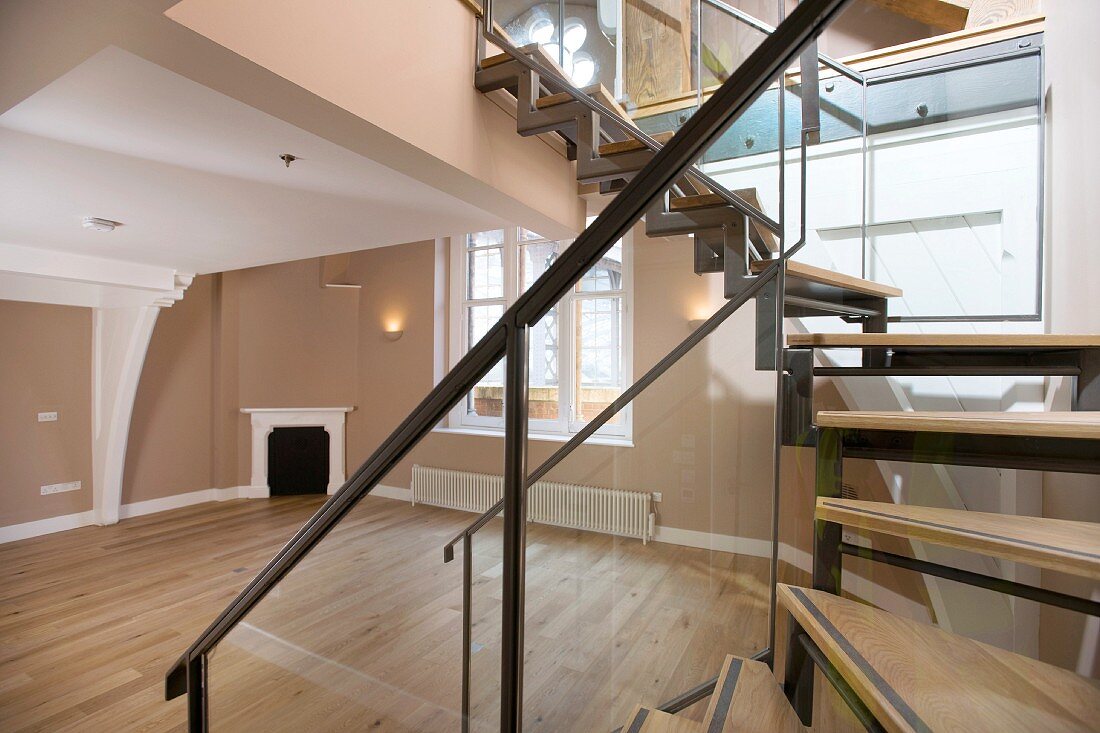 Wooden staircase leading from empty living room to mezzanine