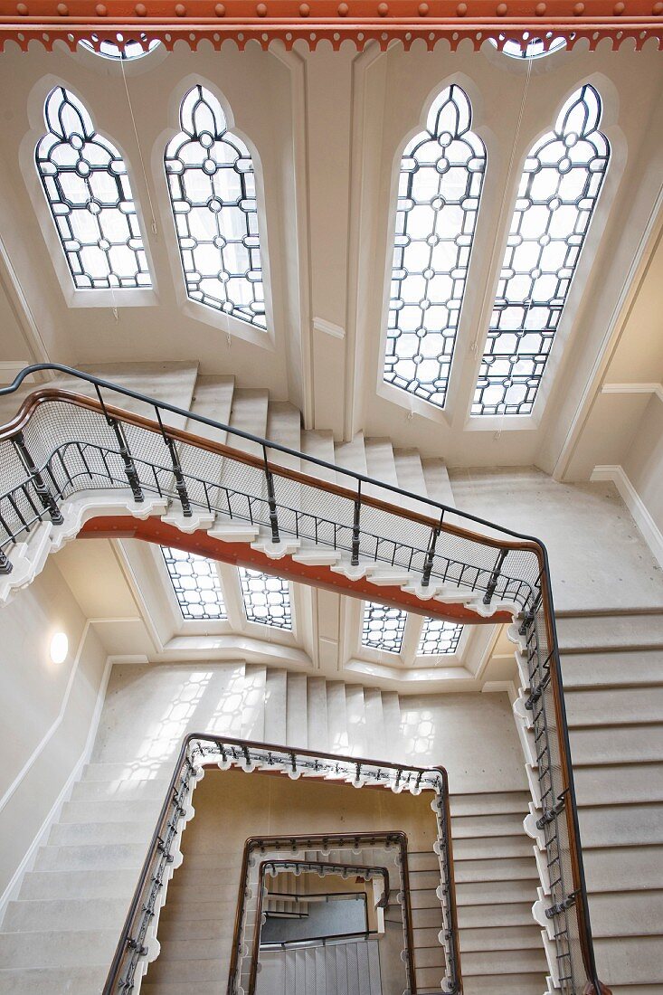 Imposantes Treppenhaus mit neugotischen Fenstern