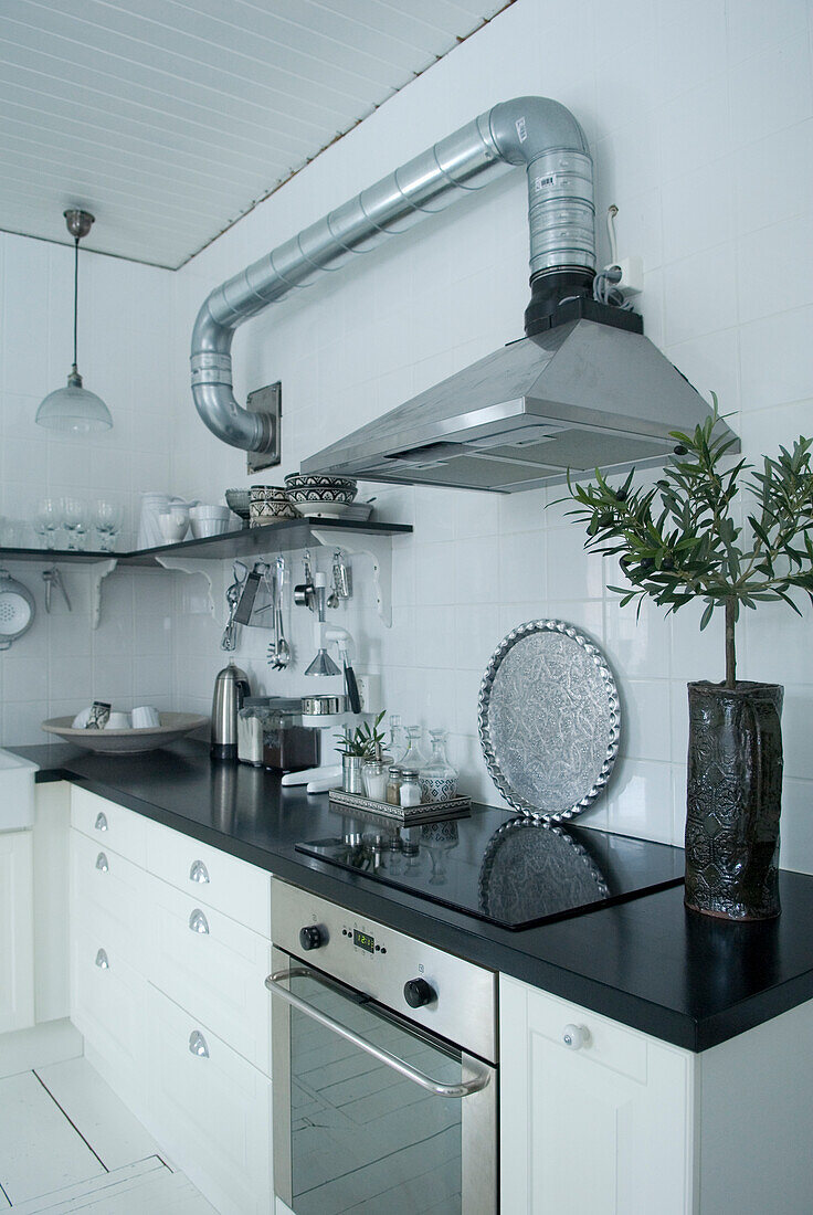 Modern kitchen in white with stainless steel elements and black worktop