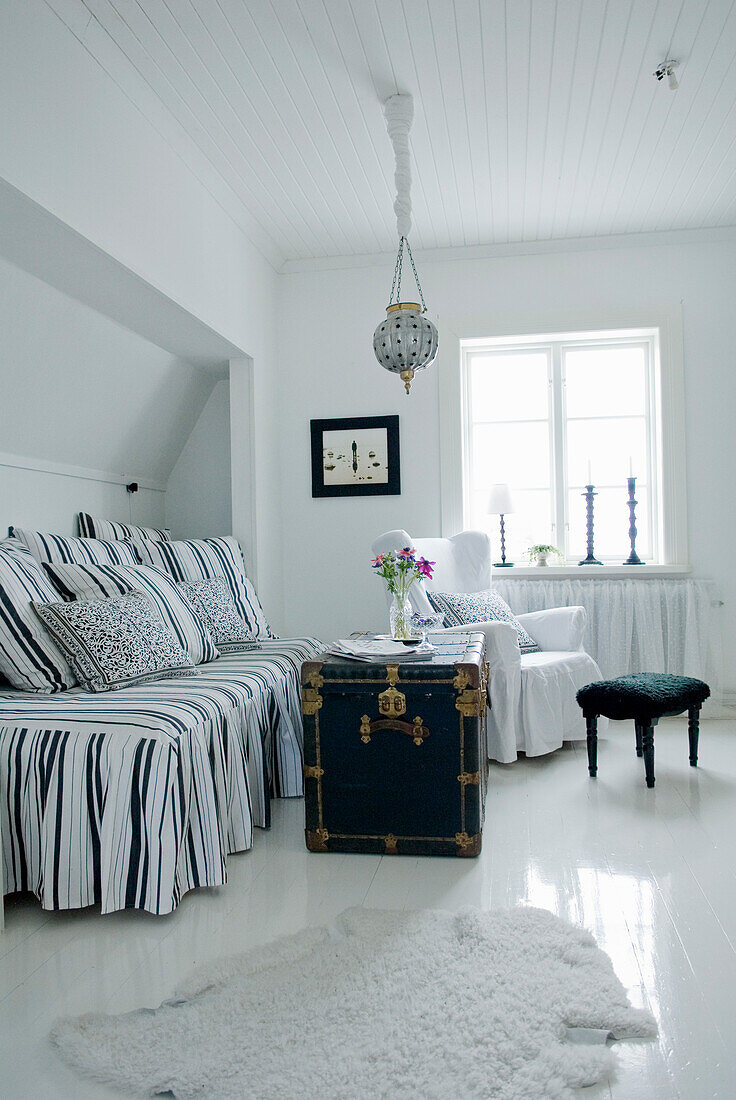 Bedroom with striped bed linen and antique chest