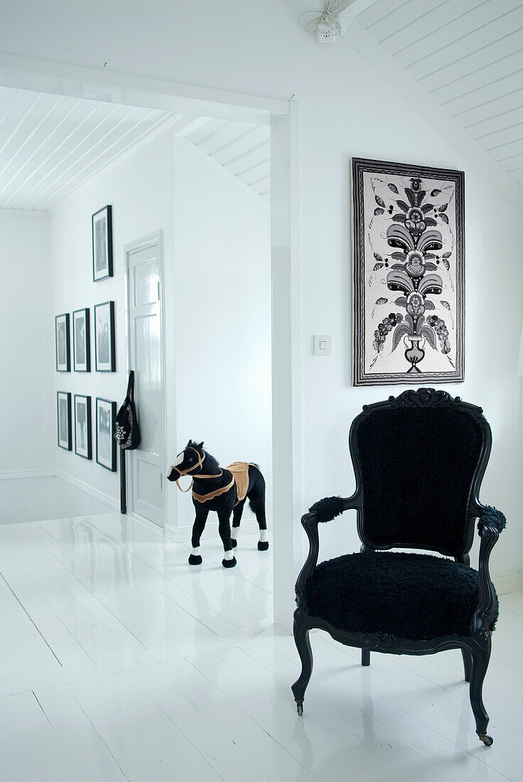 Bright hallway with black baroque armchair, play horse and white wooden floorboards