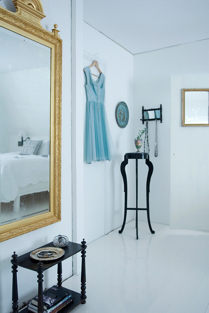 White bedroom with gold-framed mirror and black console