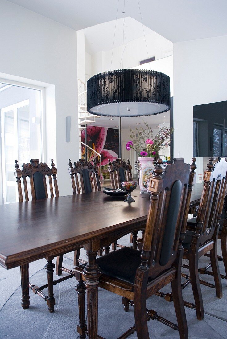 Elegant dining table and chairs in antique English style below modern pendant lamp