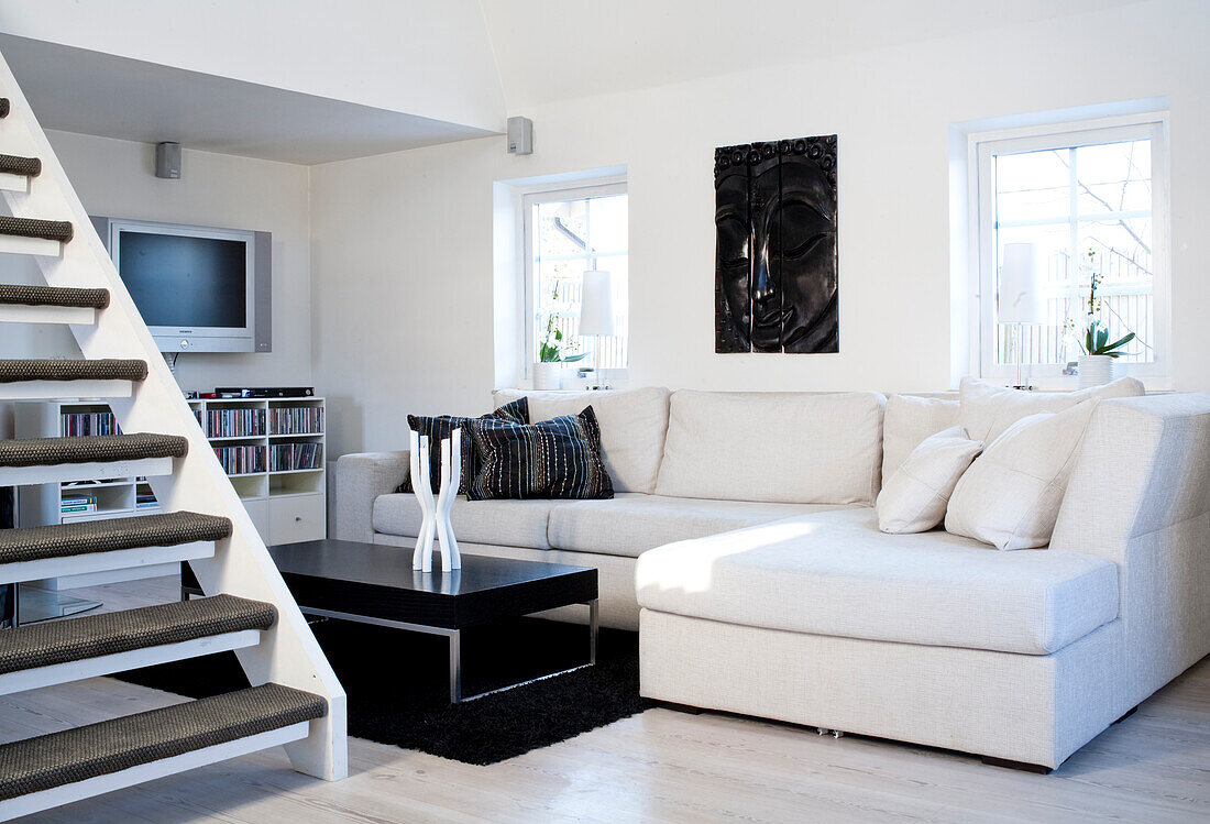 Bright living room with corner sofa, black coffee table and staircase