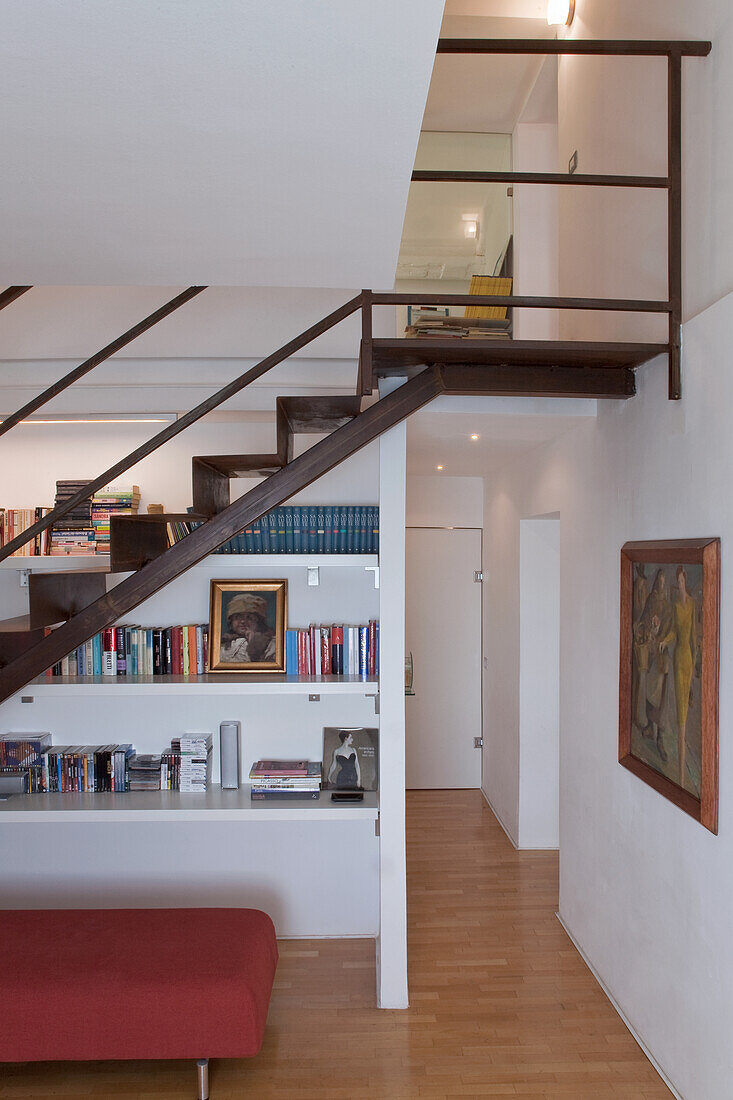 Interior with wooden staircase and gallery, bookshelf on the wall