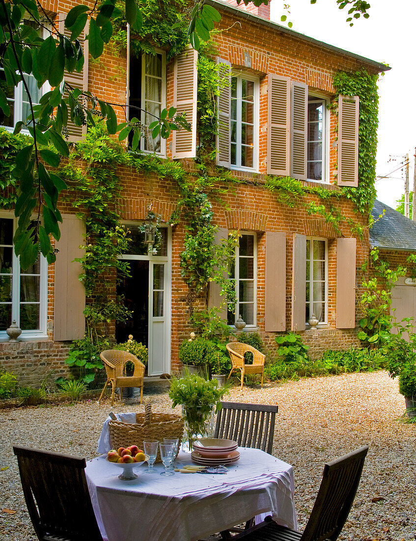 Idyllic terrace with gravel floor in front of rural house with shutters