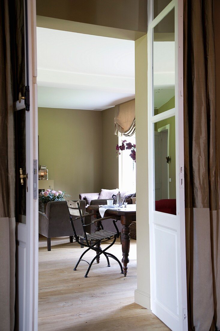 Blick durch offene Flügeltür in einen Wohnraum mit Frühstückstisch und Sofagarnitur