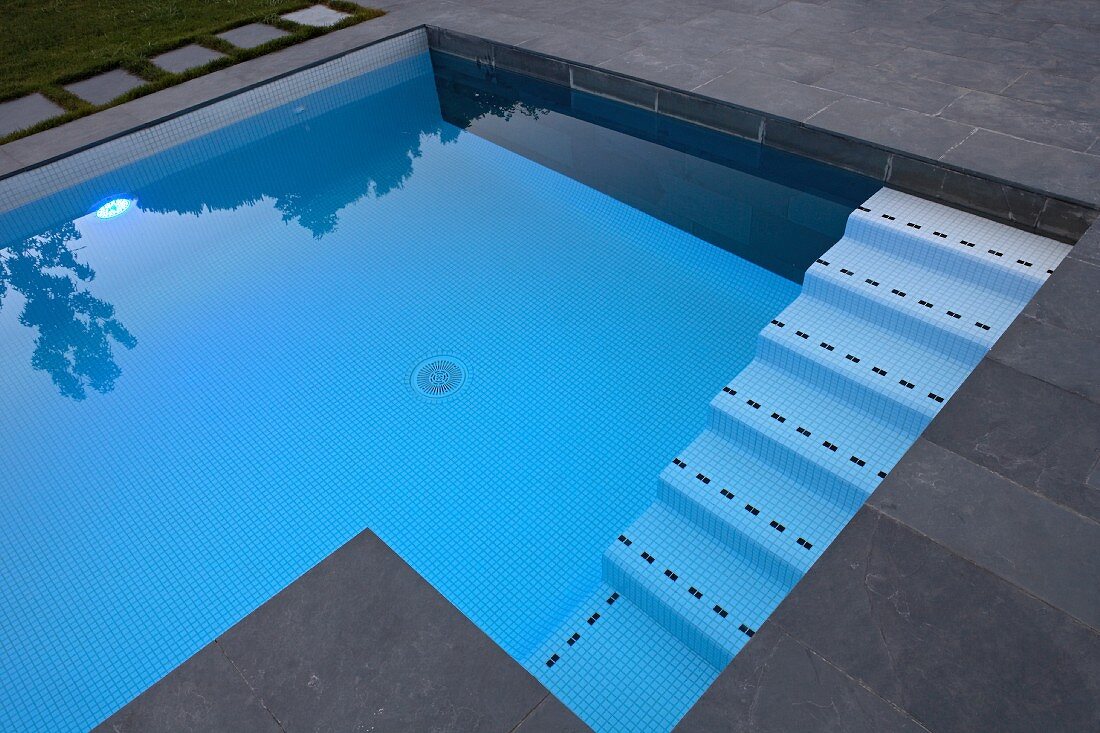 Modern pool with slate-flagged surround and mosaic tiles on steps