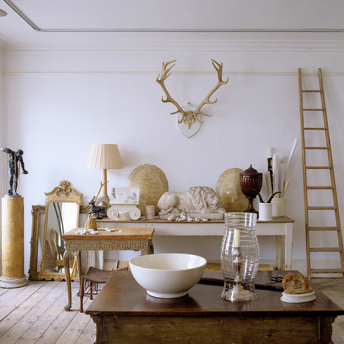 Console table with antiques and objets d'art, antlers on wall