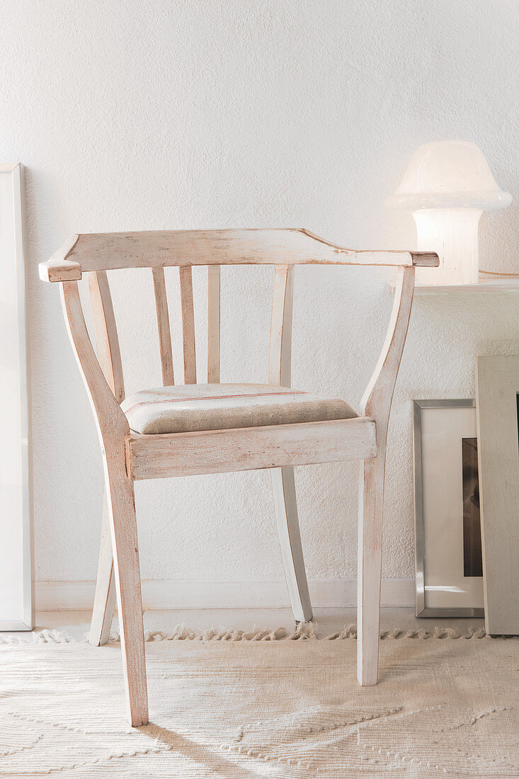 Rustikaler Stuhl mit weiss geölter Oberfläche vor Wand