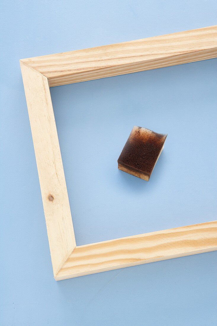 Wooden frame and sponge on blue background