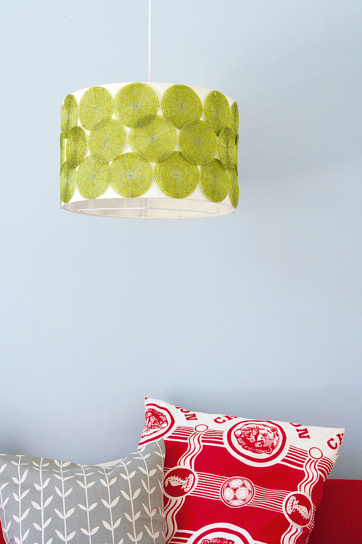 Pendant lamp with retro-patterned shade above colourful cushions