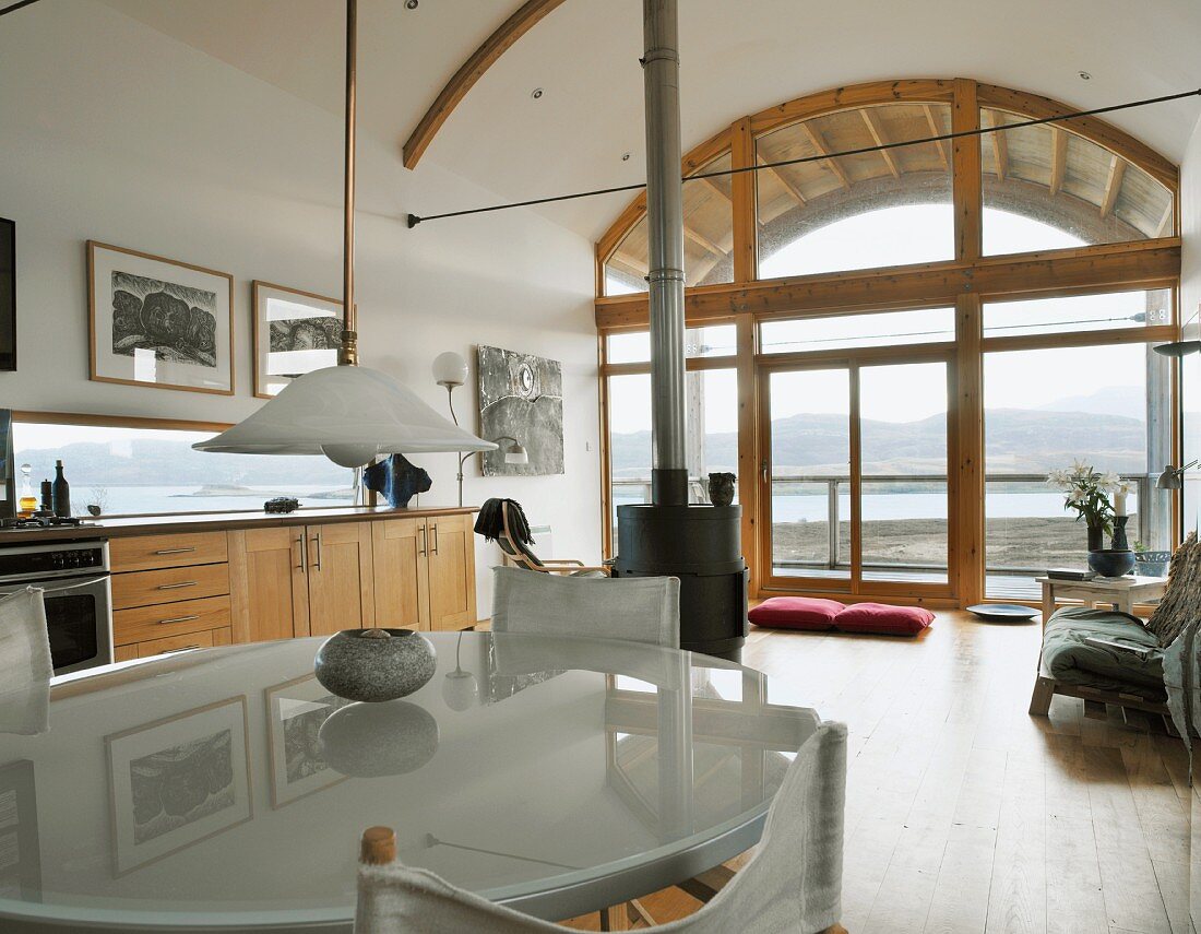 Esstisch mit moderner Milchglasplatte, Regiestühlen und Retrolampe in offenem Wohnraum mit gewölbtem Dach