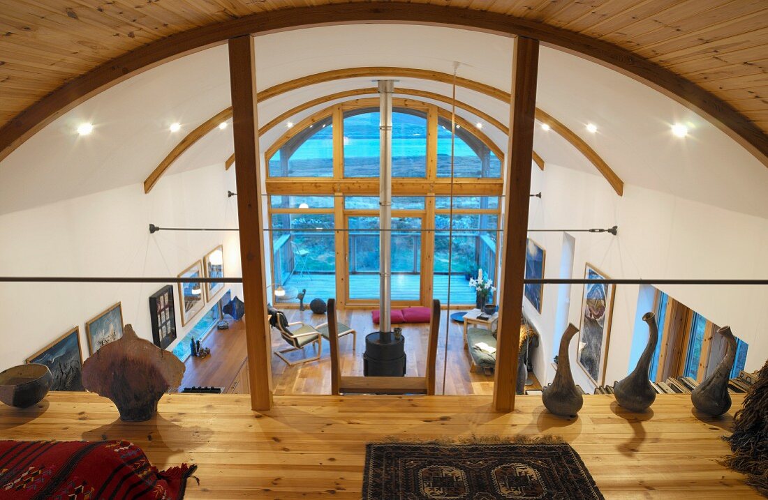 Zeitgenössische Holzarchitektur - Blick von Galerie mit Kunstobjekten auf modernen Wohnraum mit Tonnendach