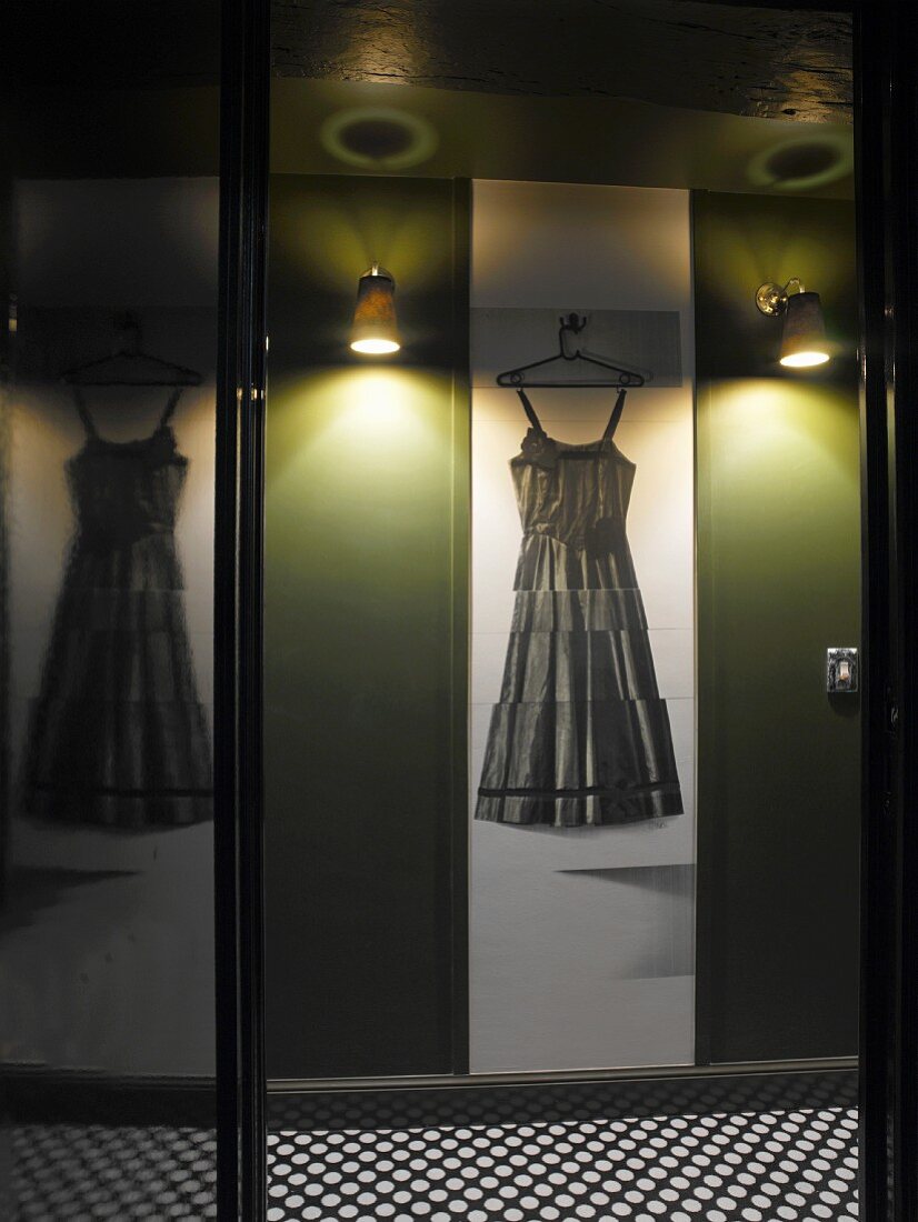 Reflections above black and white polka dot floor - dress on hanger between wall lights