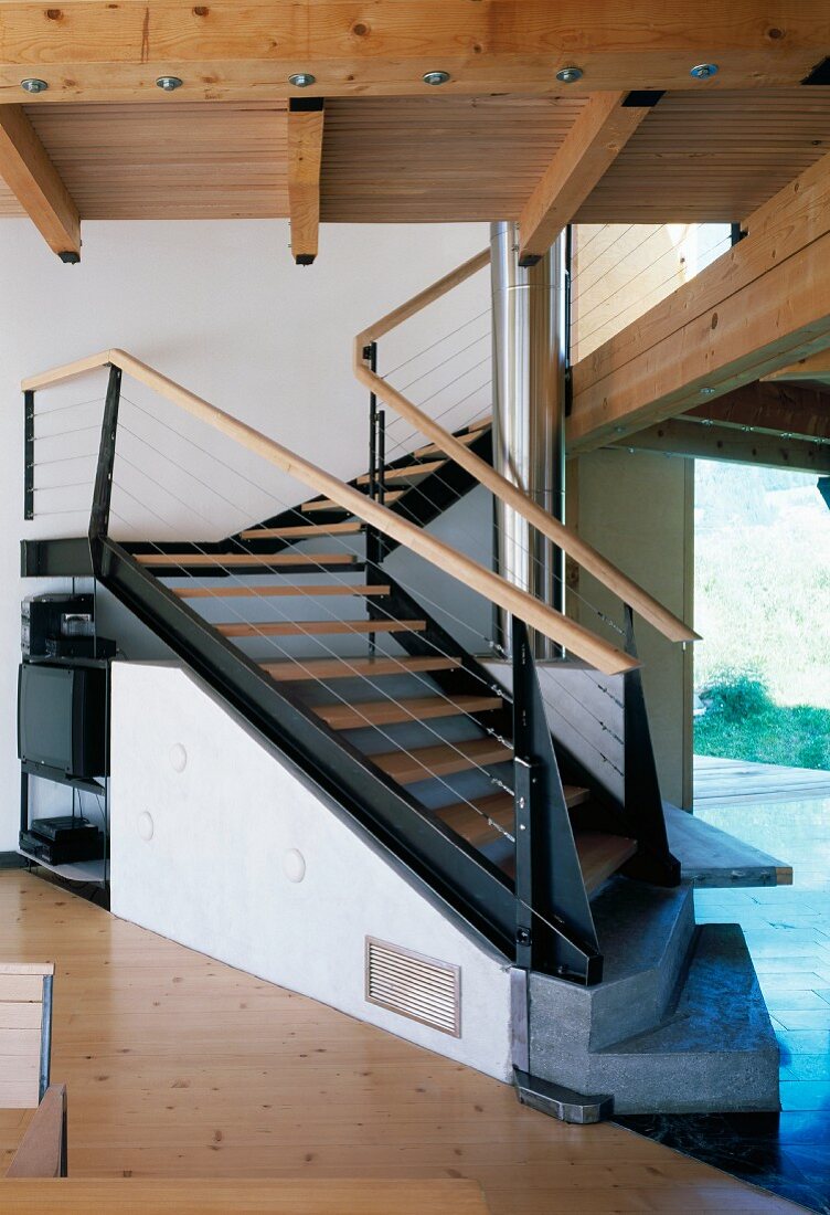 Spiral wood and steel staircase with sloping elements and stone bottom steps in contemporary, Tyrolean wooden house