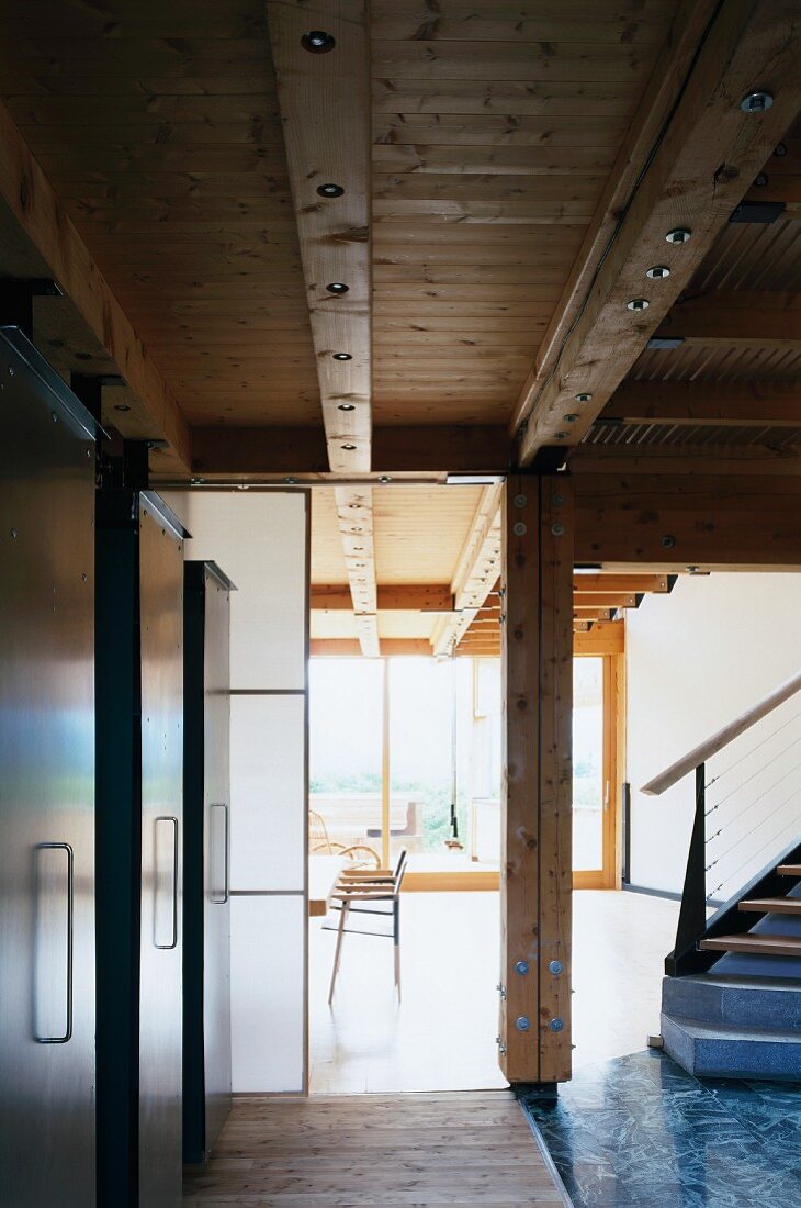 Treppe und transluzente Schiebewand im Übergang zwischen Küche und offenem Wohnraum in zeitgenössischem Holzhaus