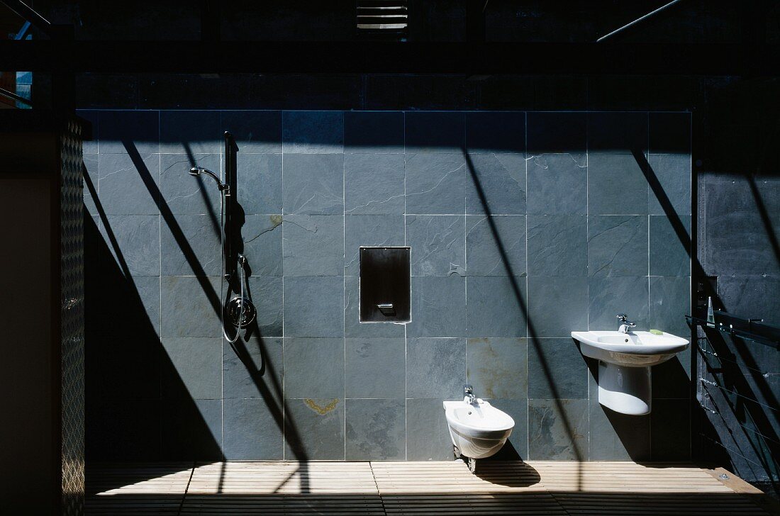 Licht- und Schattenspiel auf bläulichen Schieferfliesen in modernem Bad mit Holzrostboden