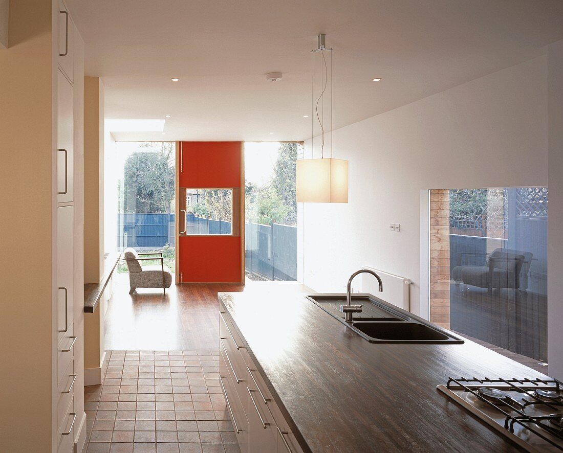Offene Küche mit Spülen- und Herdblock und Blick auf rote Haustür