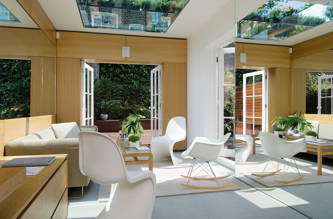 Moderne Wohnraum mit weißen Stühlen und Übergang zum Garten