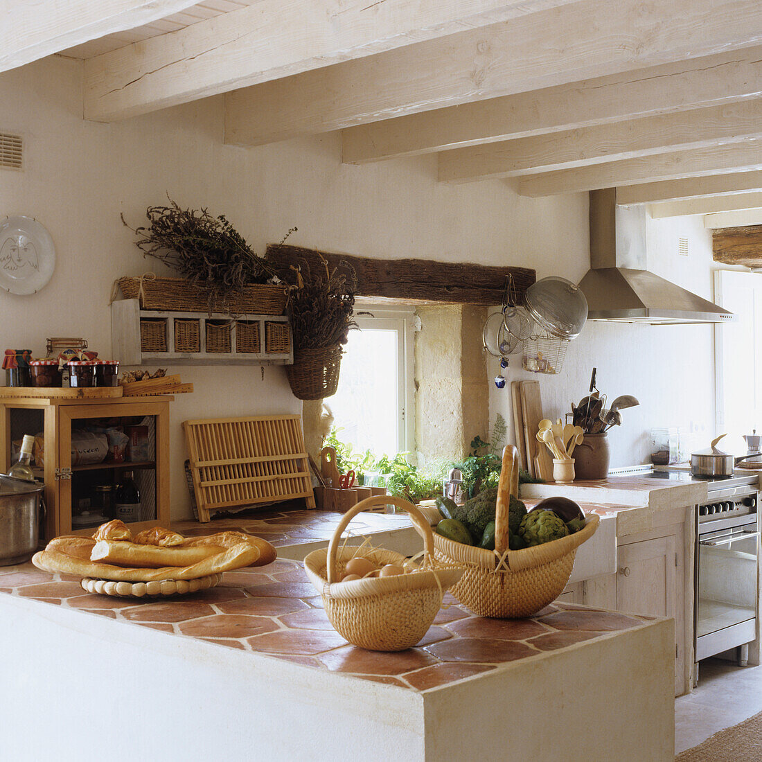 Küche mit Arbeitsplatte aus Terrakottafliesen und Holzbalkendecke in einem Landhaus