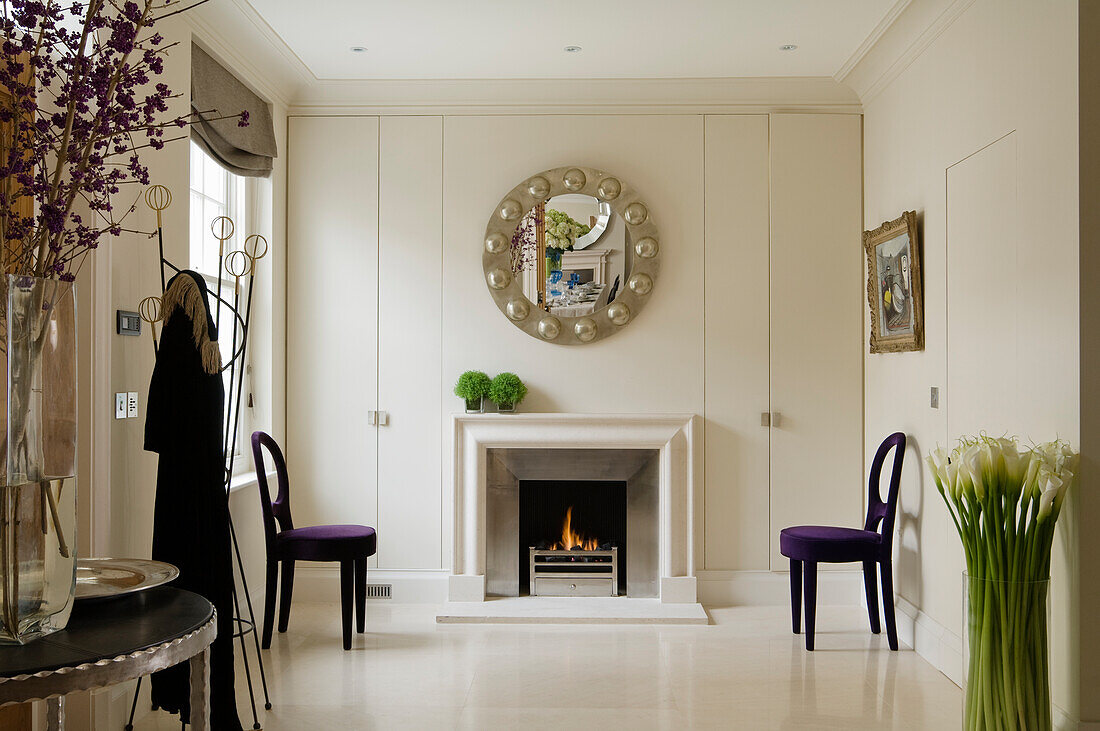 Room with fireplace, mirror, painting and chairs with purple upholstery