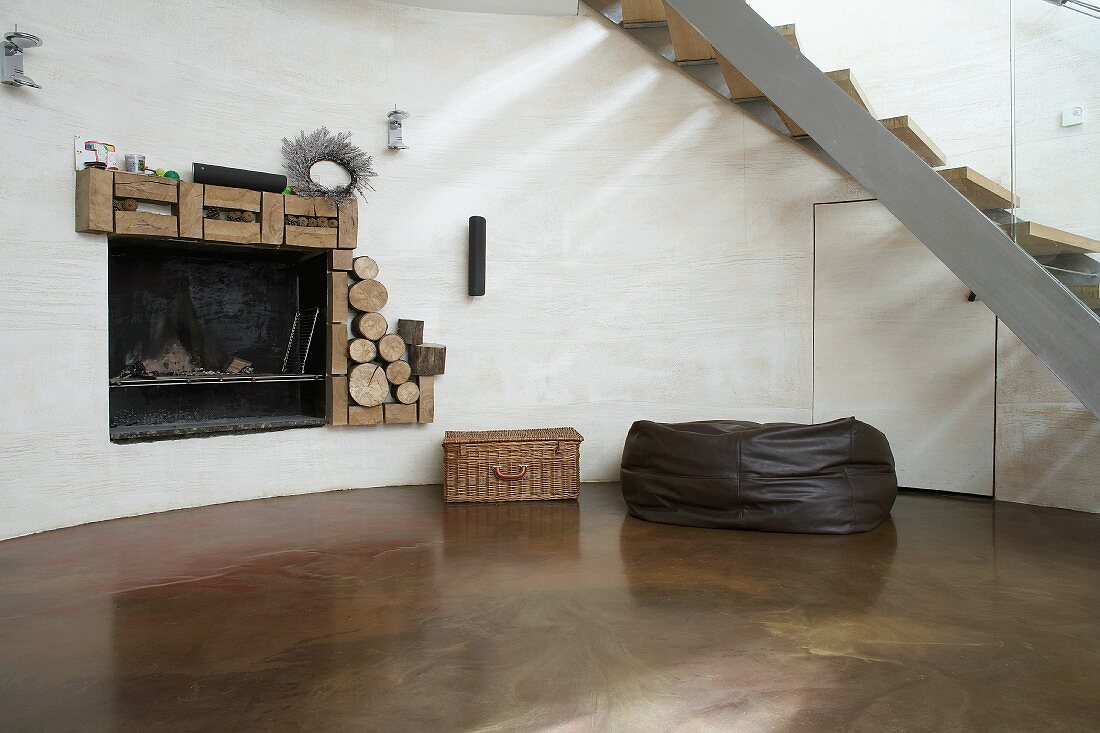 Runde Kaminecke mit poliertem Betonboden unter Treppe mit frei gebogener Stahlwange