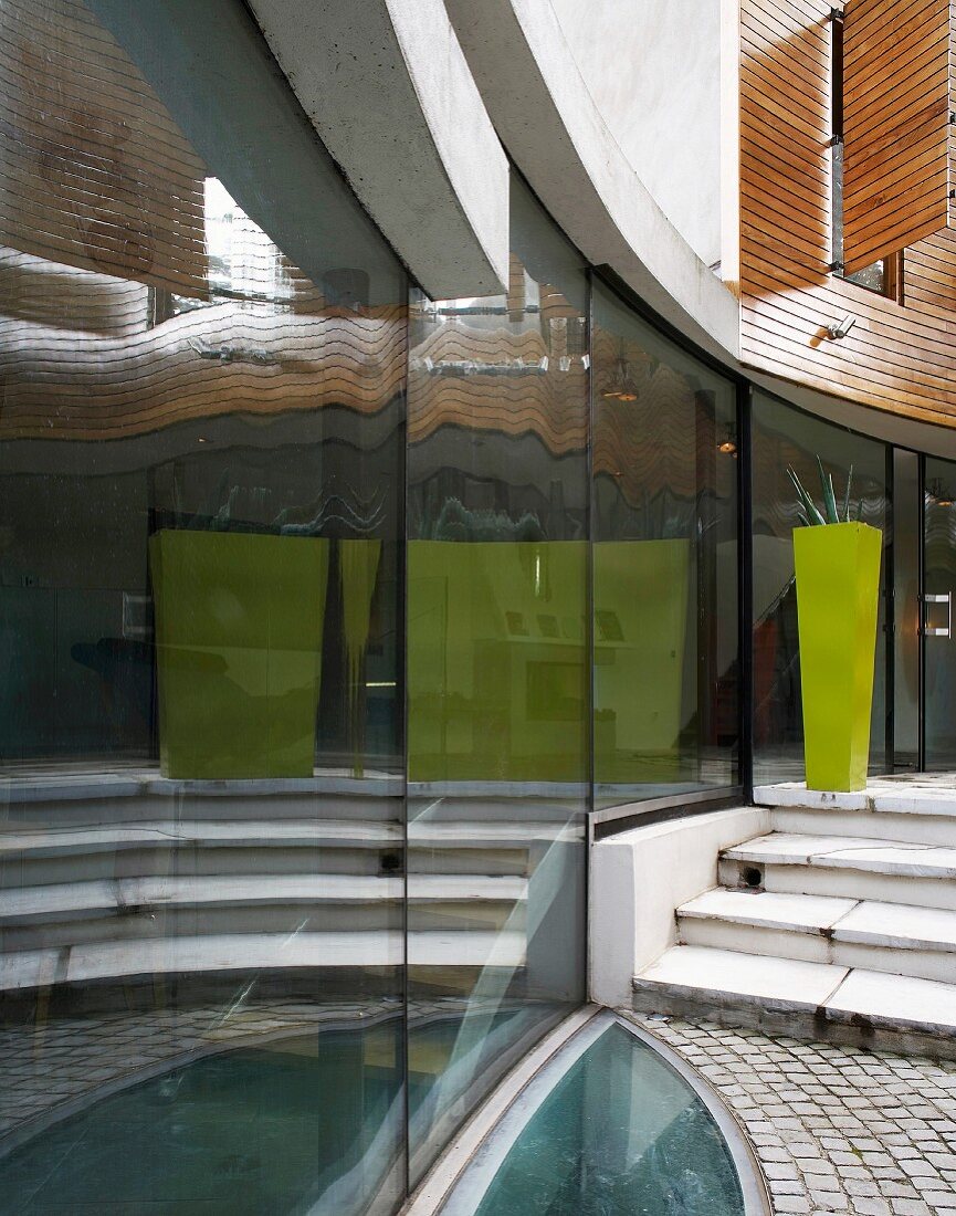 Terrasse an zeitgenössischem Wohnhaus - Spiegelung in gebogener Glasfassade und ellipsenförmiger Glasboden für Kellerbelichtung
