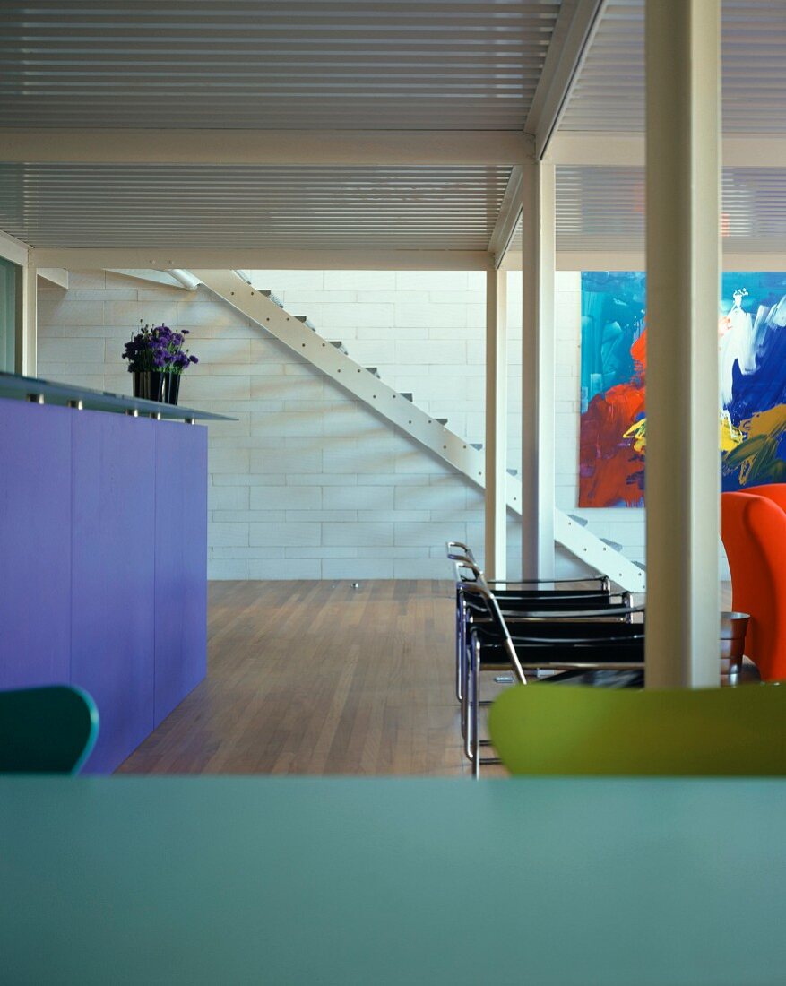 Küchentheke, Sitzmöbel und moderne Kunst in klaren, kräftigen Farben in Wohnraum mit Stahlstützen und Trapezblech-Decke