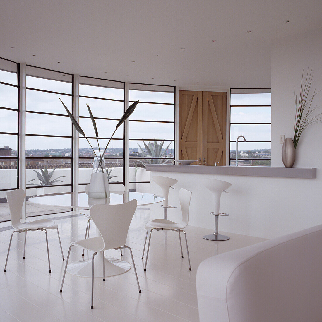 Bright room with white chairs and glass table in front of floor-to-ceiling windows