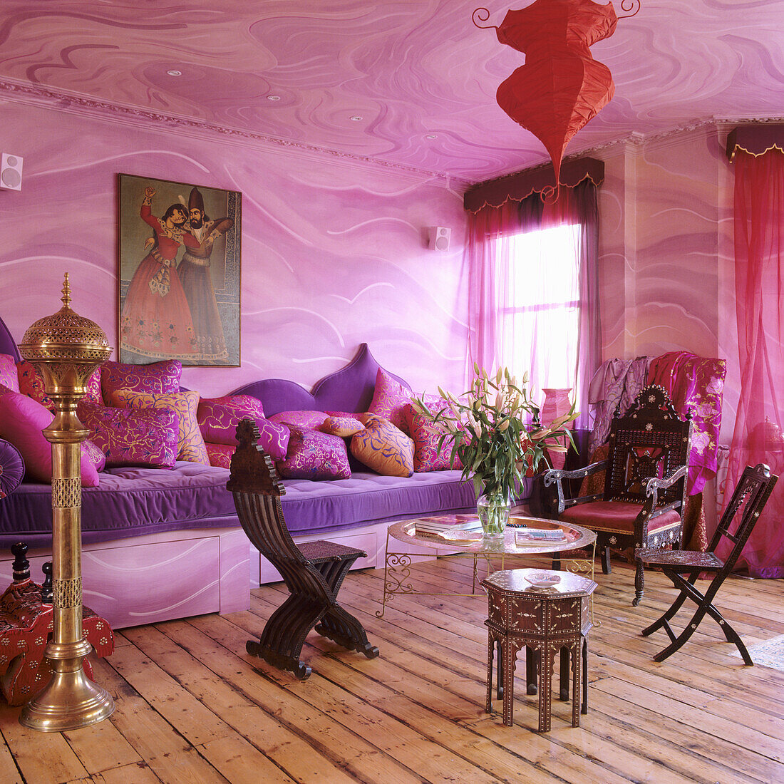 Oriental-style living room with purple sofa, pink walls and red curtains