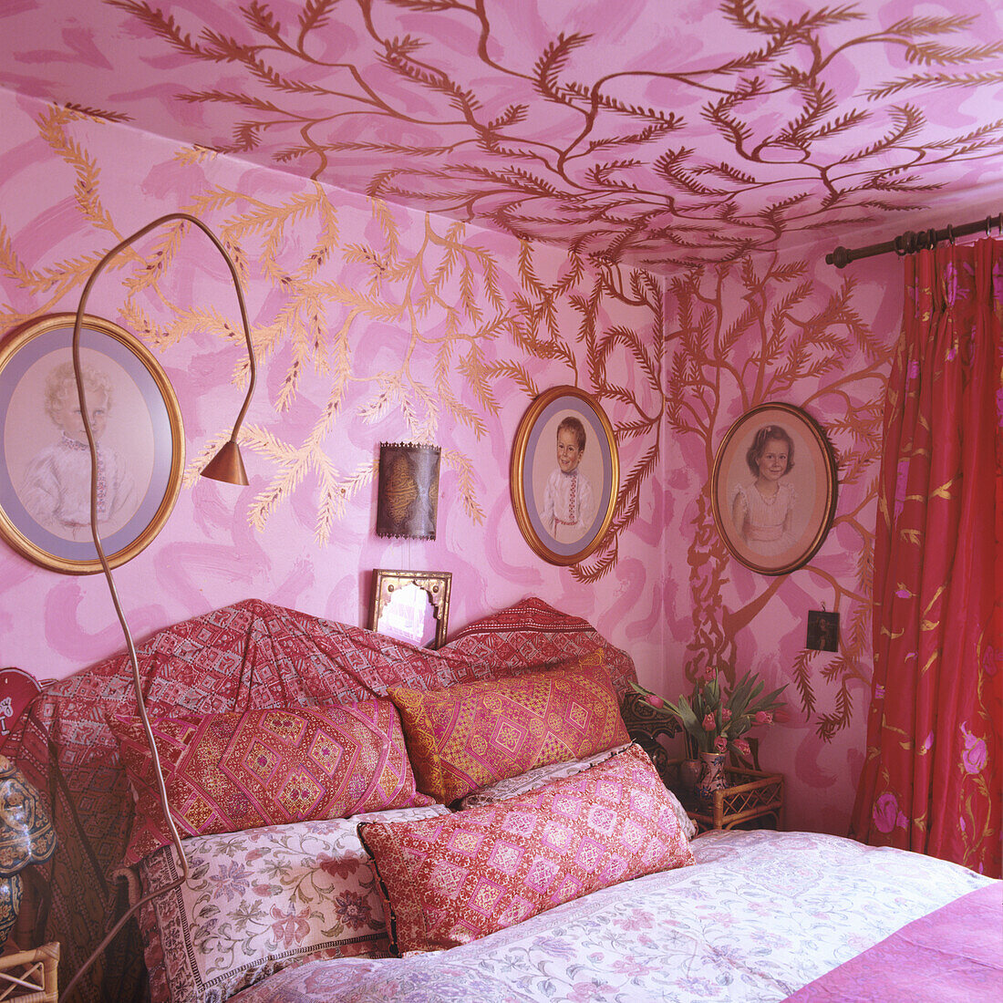 Bedroom in shades of pink and red with wall and ceiling design in gold and pictures