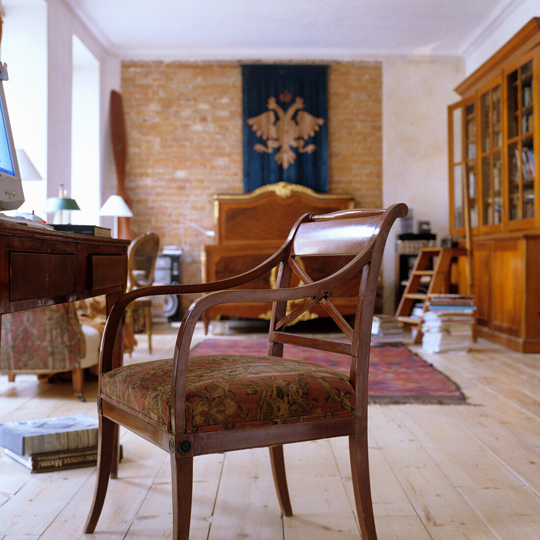 Wooden floor and antique furniture in room with brick wall