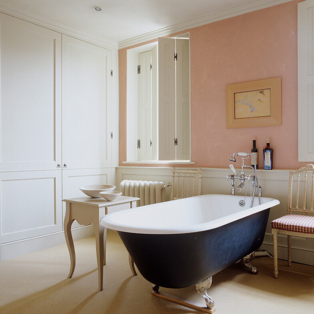 Freestanding bathtub in classic bathroom with pink accent wall