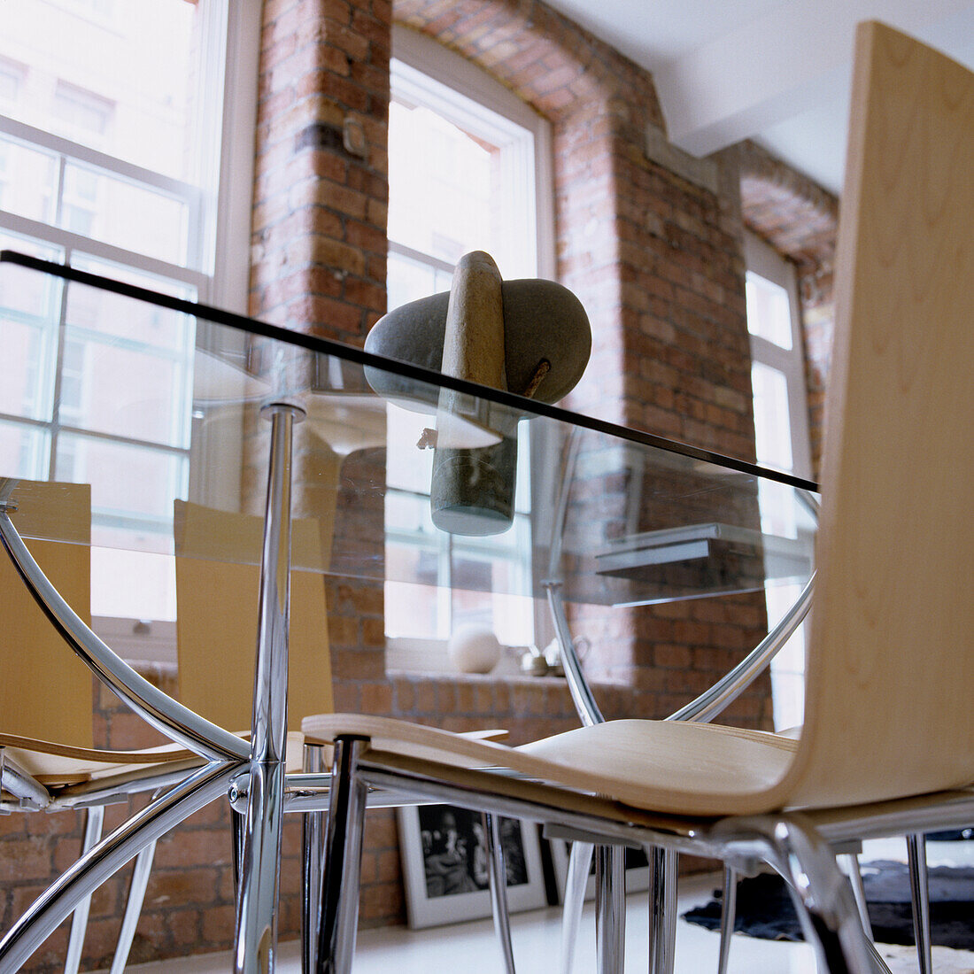 Glass dining table in room with brick walls and large windows