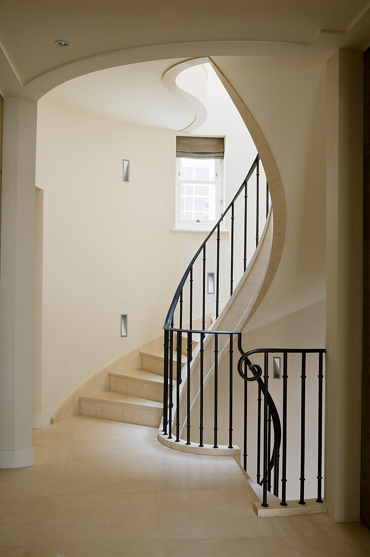 Steintreppe mit schwarzem Geländer in hellem Treppenhaus