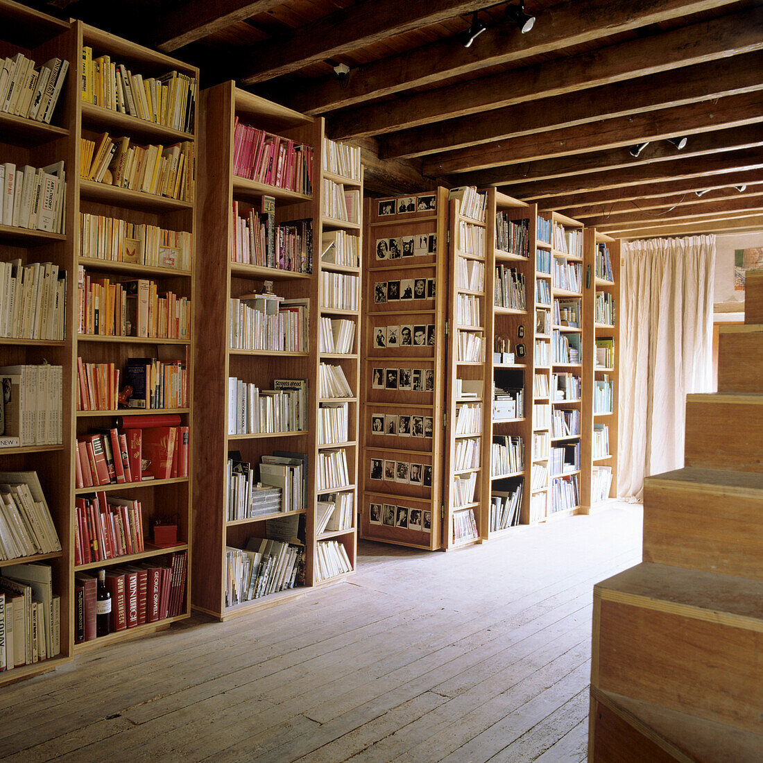 Bibliothek mit deckenhohen Bücherregalen unter Holzbalkendecke, Holzboden