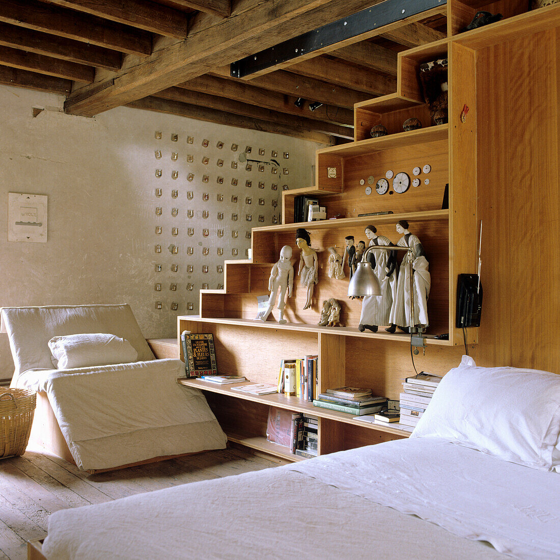 Bedroom with wooden beamed ceiling, shelf under steps and armchair